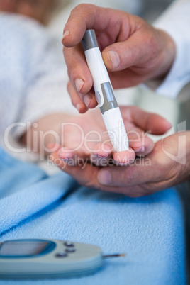 Doctor testing diabetes of senior patient with insulin pen