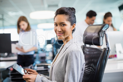 Smiling business executive using digital tablet at desk in office