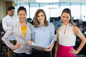 Smiling business colleagues discussing over clipboard at desk in office