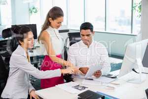 Business colleagues discussing over digital tablet at desk in office