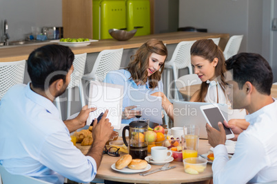 Business colleagues discussing over digital tablet while having breakfast