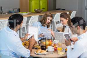 Business colleagues discussing over digital tablet while having breakfast