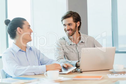 Smiling business executives discussing with each other in conference room