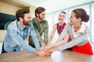 Business executives with their hands stacked on wooden table