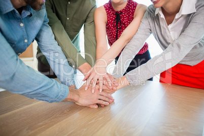 Business executives with their hands stacked on wooden table