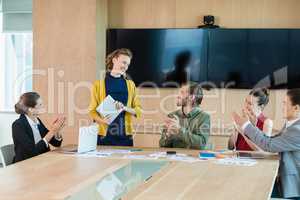 Business team applauding their colleague in conference room