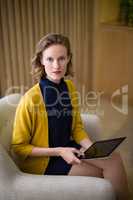 Confident business executive sitting with digital tablet on sofa
