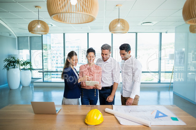 Smiling architects discussing over digital tablet