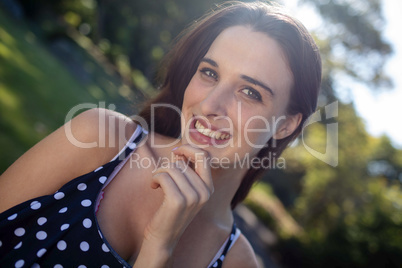 Woman with hand on chin while standing in park