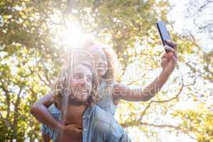 Couple taking selfie while enjoying piggyback ride