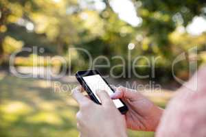 Womans hand using a mobile phone in the park