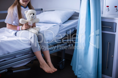 Patient sitting with teddy bear on hospital bed