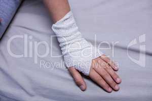 Girl with injured hand sitting on stretcher bed