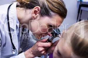Female doctor examining patient ear with otoscope