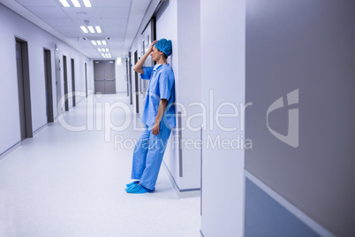 Sad surgeon leaning on wall in corridor