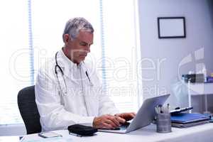 Doctor sitting at table and using laptop