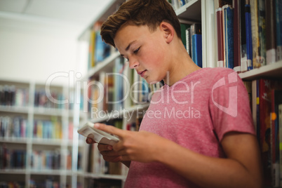 Happy schoolboy using digital tablet in library