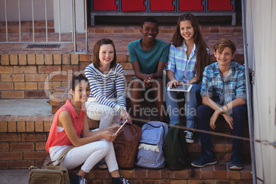 Students using digital tablet on staircase