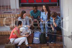 Students using digital tablet on staircase