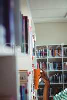 Schoolboy selecting book in library