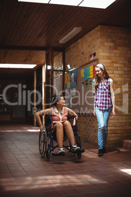 Schoolgirl talking with her disabled friend in corridor
