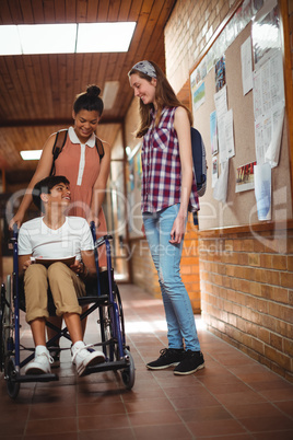Schoolgirls talking with her disabled friend in corridor