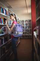 Schoolgirl selecting book in library