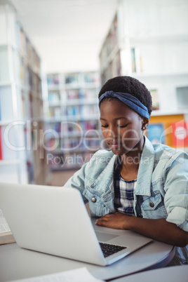 Schoolgirl using laptop in library