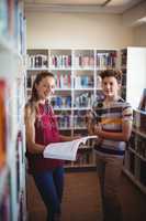 Portrait of happy classmates standing in library