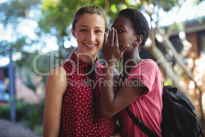 Schoolgirl whispering in her friends ear