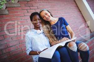 Portrait of happy schoolgirls reading book