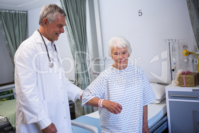 Doctor assisting senior patient in ward