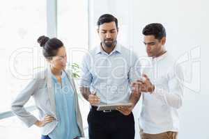 Business colleagues discussing over digital tablet in office
