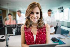 Smiling business executive using digital tablet at desk in office