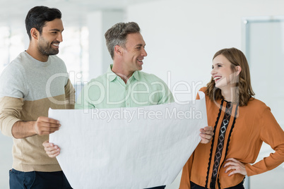 Smiling business colleagues discussing over blueprint