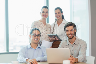 Smiling business executives using laptop and digital tablet in conference room