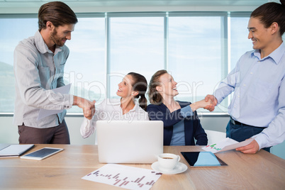 Smiling business executives shaking hands with each other in conference room