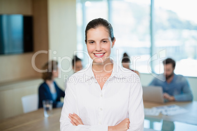 Beautiful business executive standing with her arms crossed in office