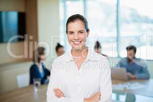 Beautiful business executive standing with her arms crossed in office