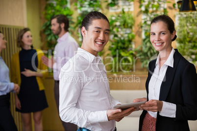 Business executives smiling while using digital tablet at office