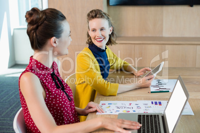 Smiling business executives interacting with each other in conference room