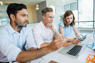 Architects discussing over laptop in conference room