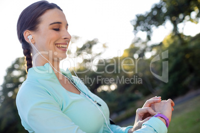 Smiling female jogger checking her fitness band