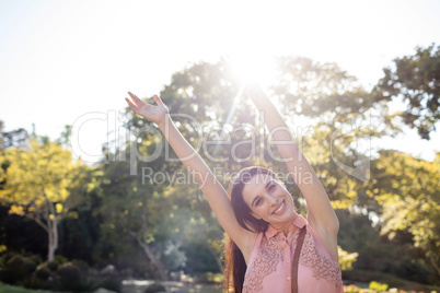 Happy woman standing in the park with her hands raised