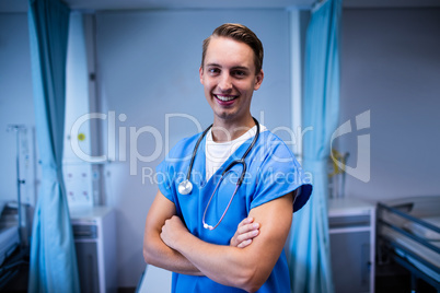Portrait of male doctor standing with arms crossed in ward
