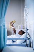 Patient playing with teddy while resting on the bed