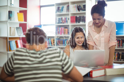 Happy students using laptop in library