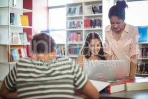 Happy students using laptop in library