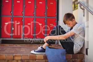 Sad schoolboy sitting on staircase