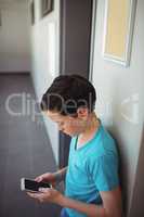 Schoolboy using mobile phone in corridor at school